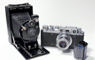 Zwei analoge Kameras und eine Filmpatrone werden in diesem Schwarz/Weiss-Bild gezeigt